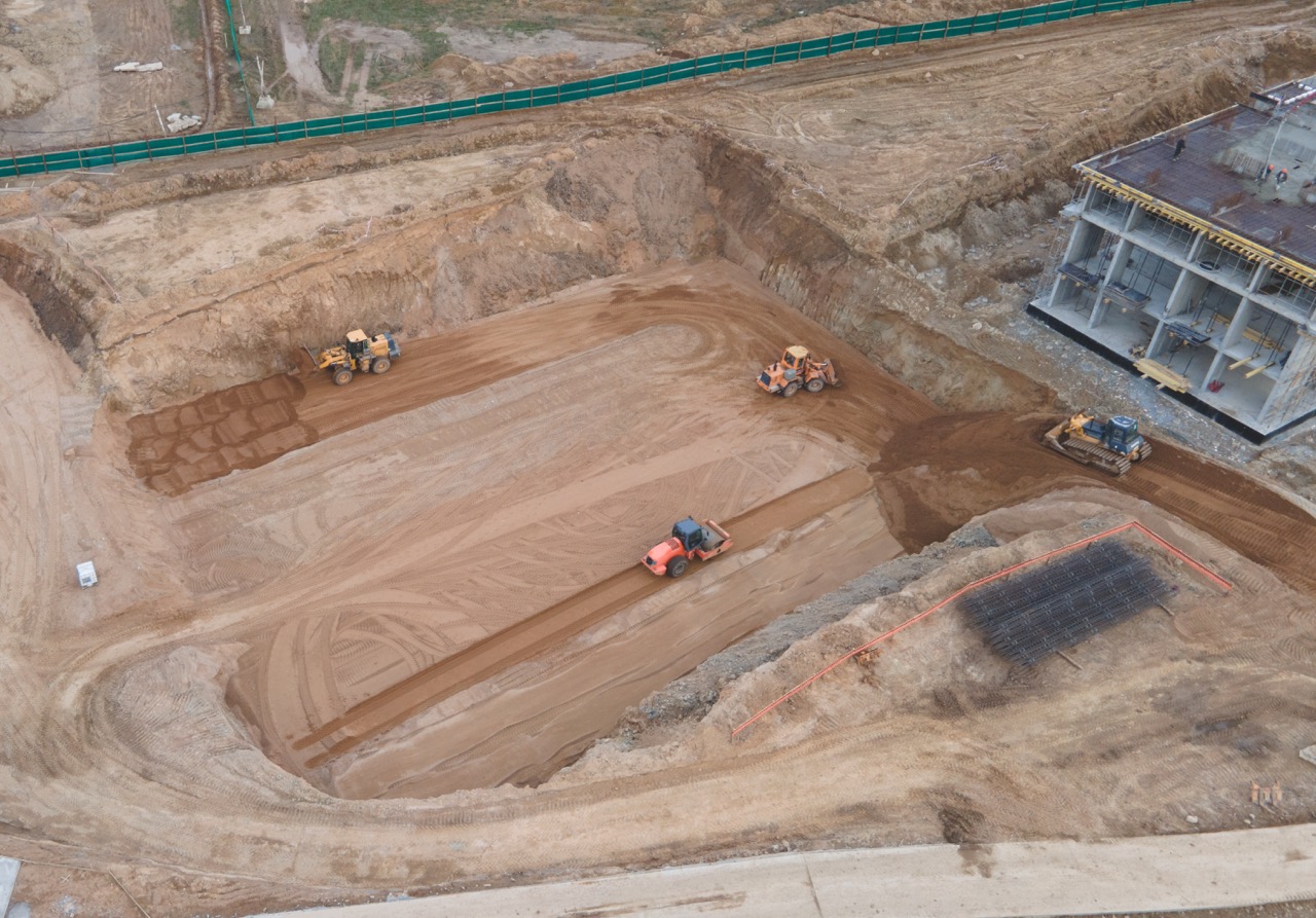 Vibration road roller and wheel loader leveling ground for construct of foundation. Soil Compactor compresses soil under the formwork. Dozer at construction site.
