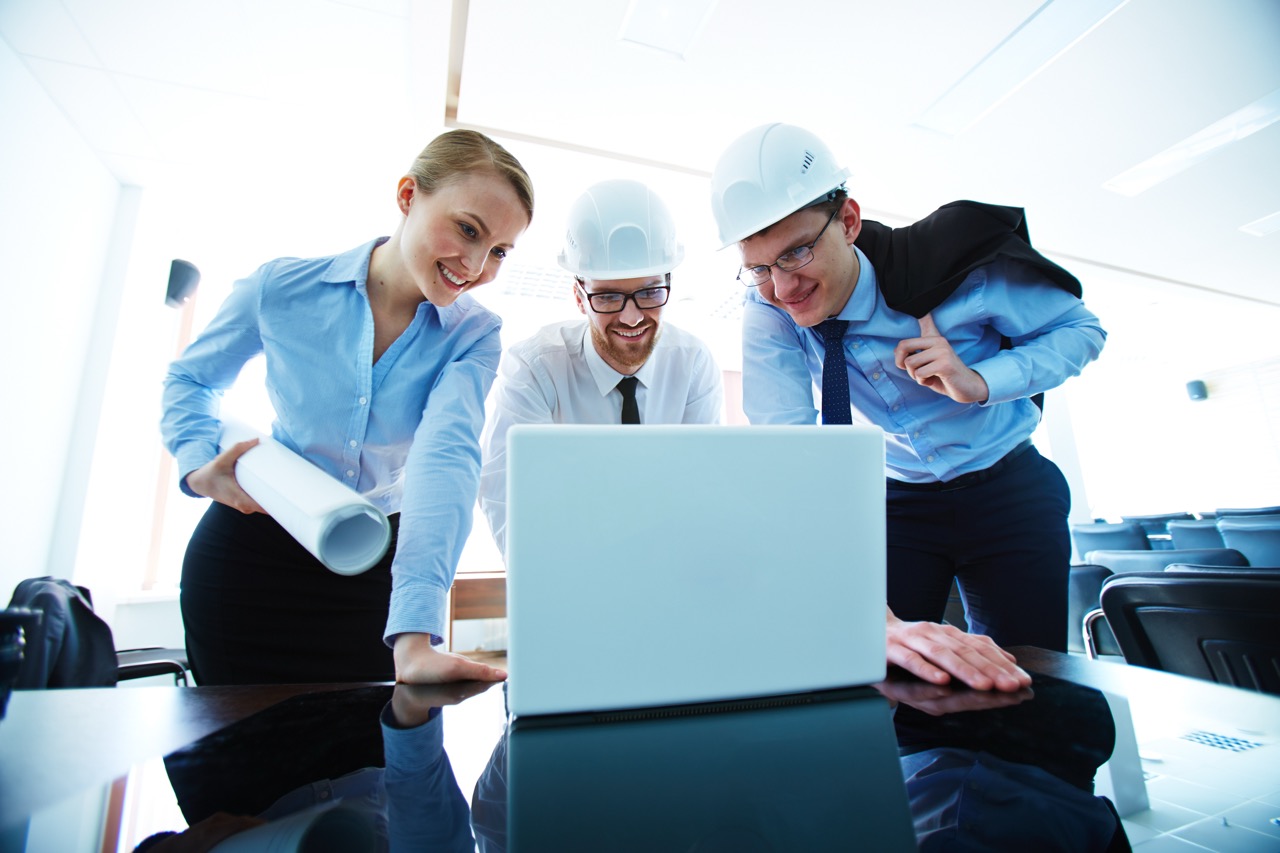 Group of young architects looking at laptop display in office
