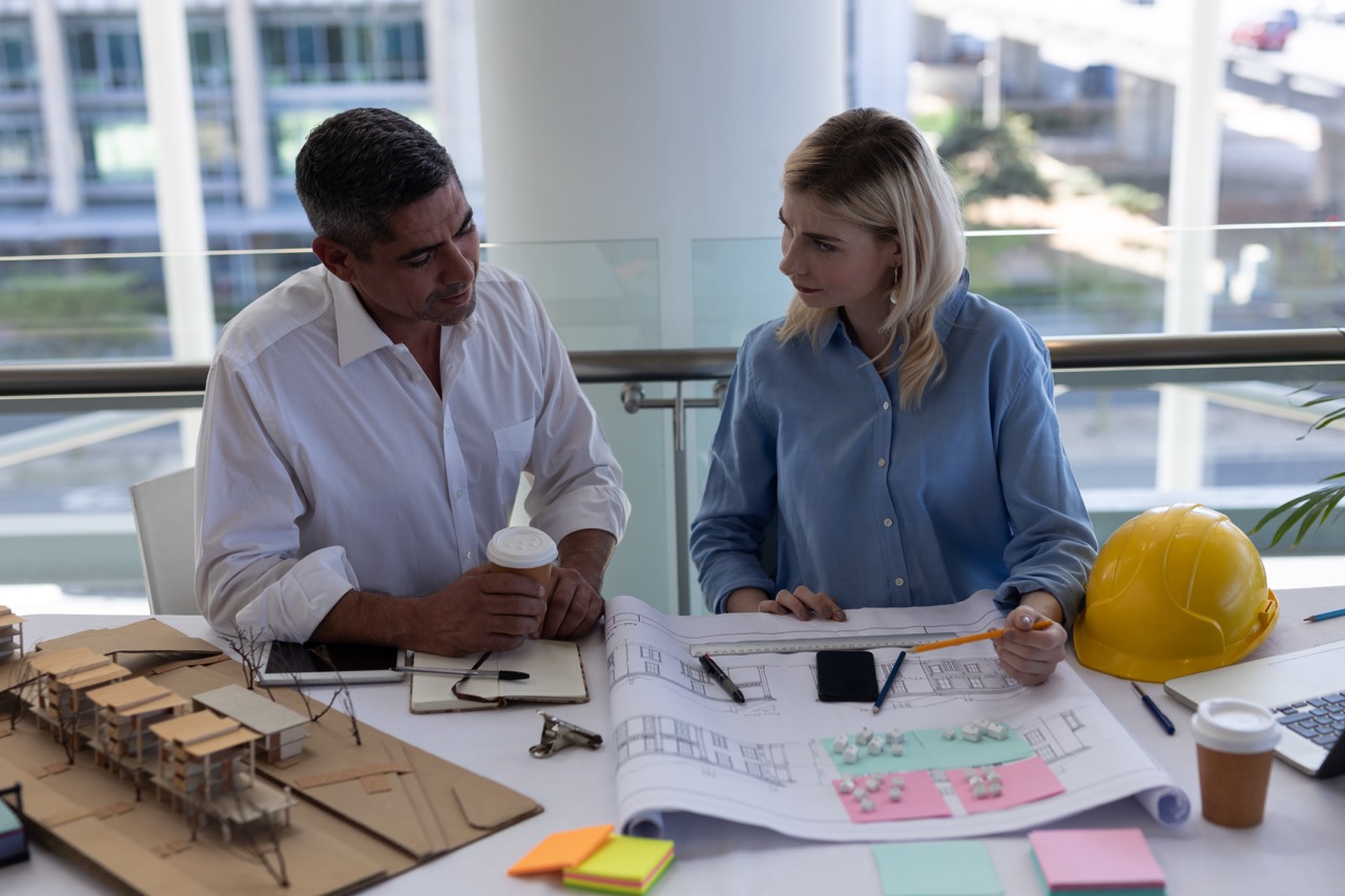 Front view of Caucasians architects discussing over blueprint at desk in modern office