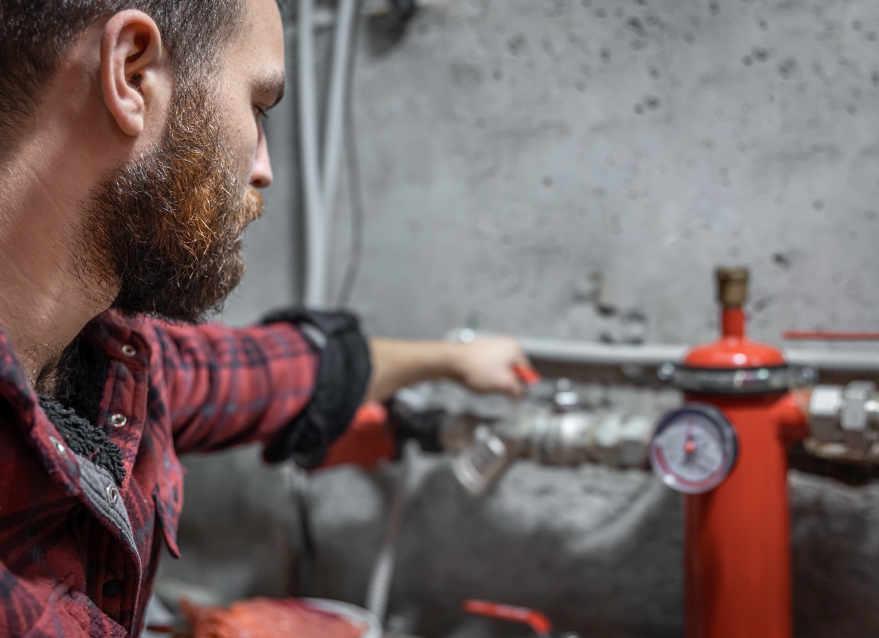 The man looks at the expansion tank, faucet, pipes, valve, pressure meter, copy space.