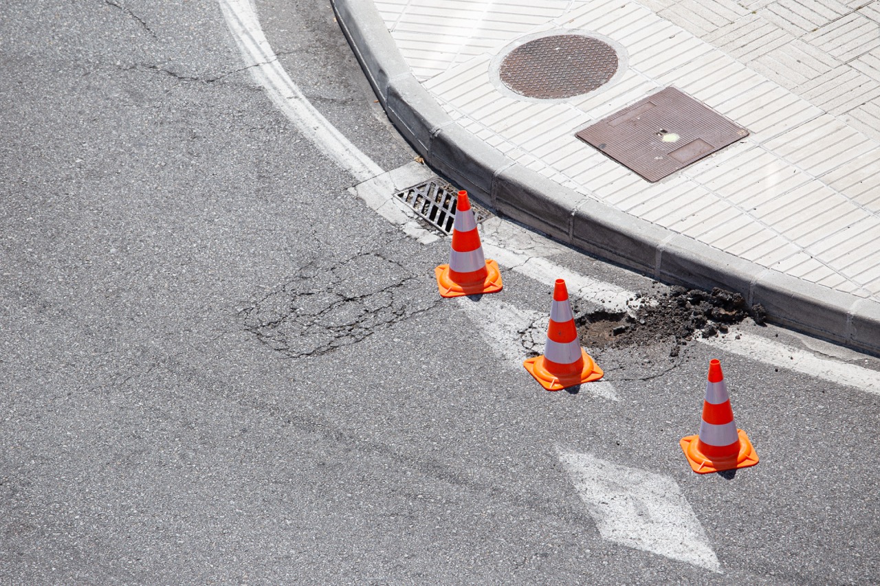 Damaged city road marked with cones awaiting to repair