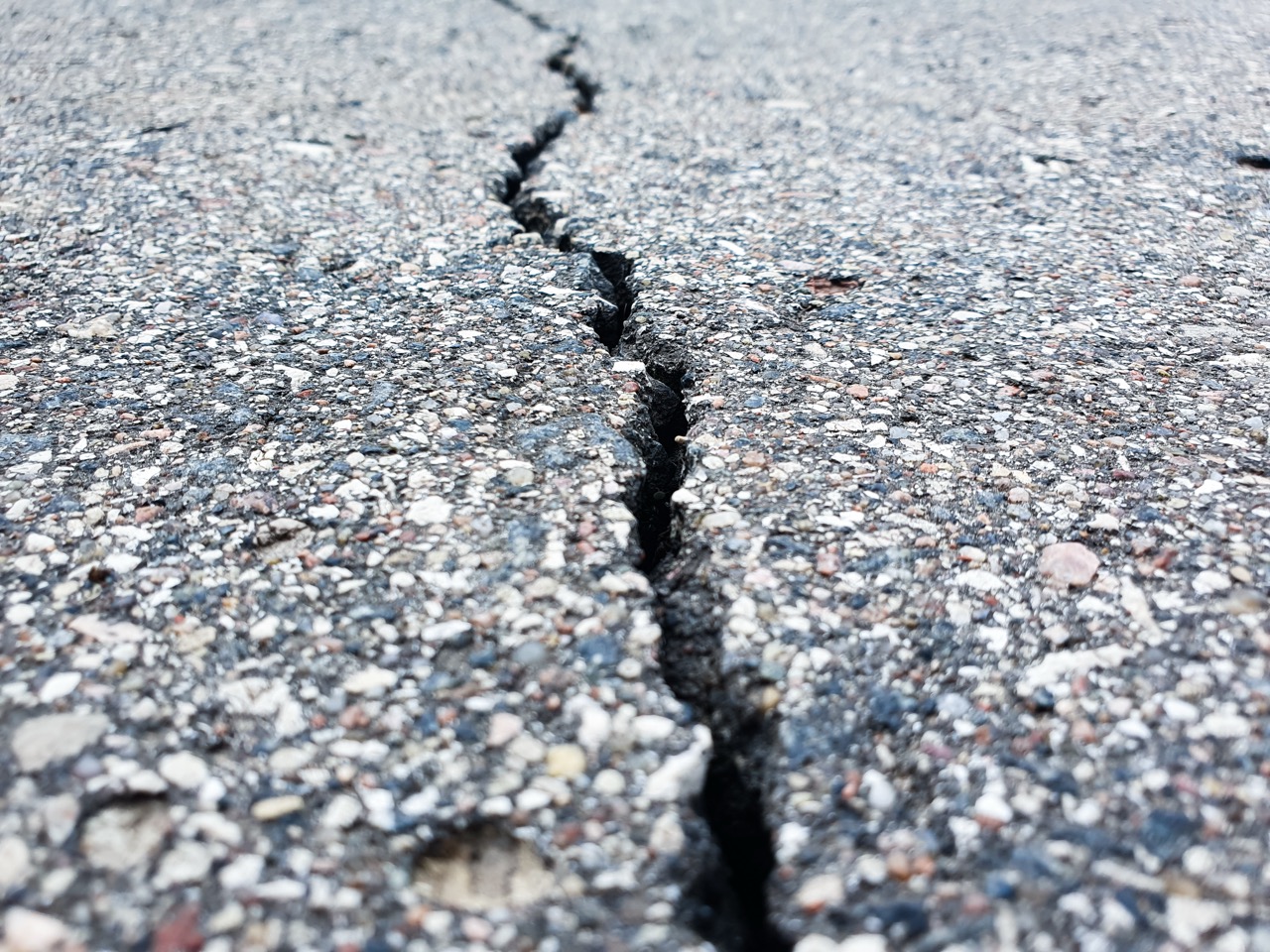 Cracked asphalt pavement. Cracked asphalt,road,highway,road shoulder,roadway damage. Emergency condition of the asphalt, damage.